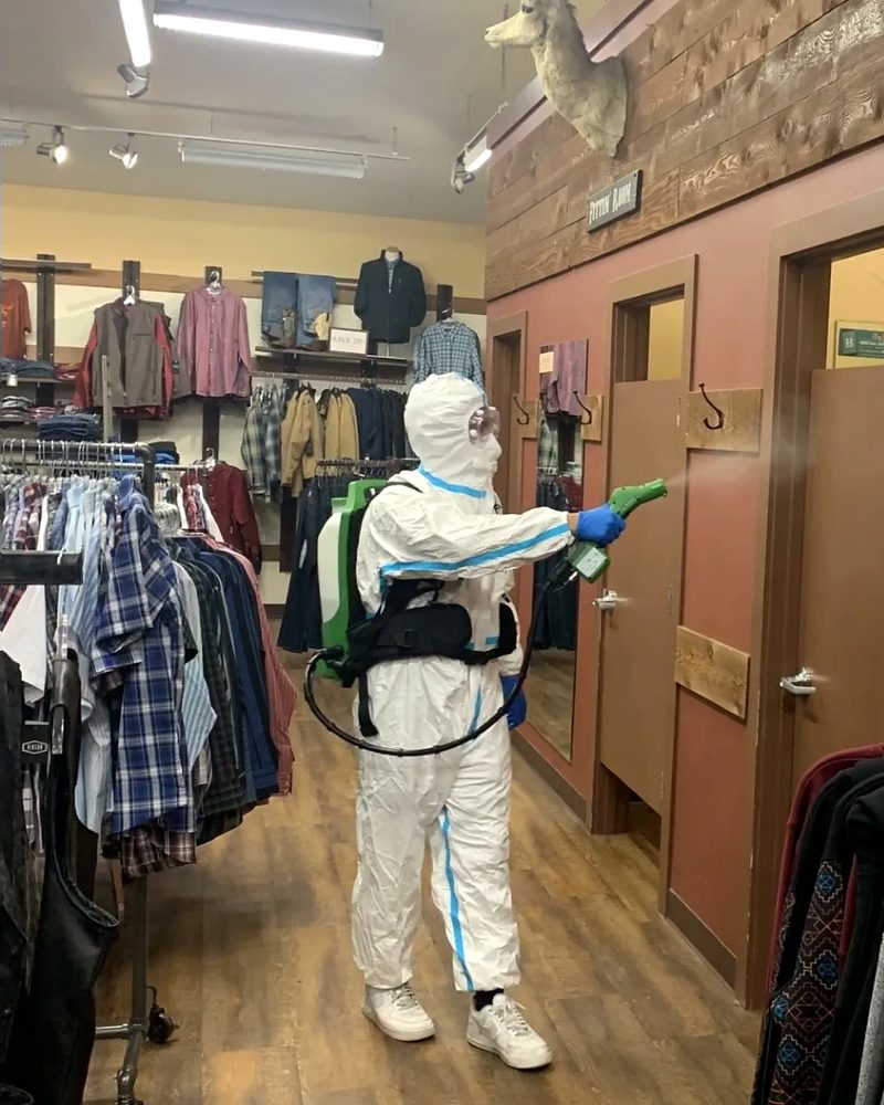 A crew member in protective gear spraying a clothing store