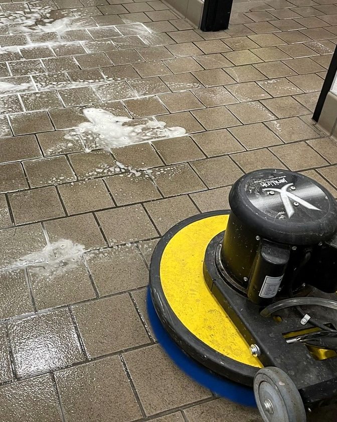 A floor machine scrubbing a tile floor
