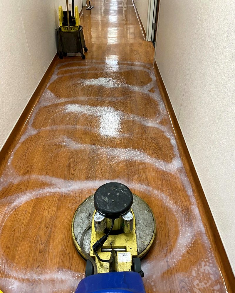 A floor machine stripping a wood corridor floor